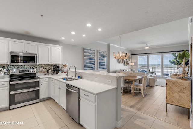 kitchen featuring appliances with stainless steel finishes, tasteful backsplash, white cabinetry, sink, and kitchen peninsula