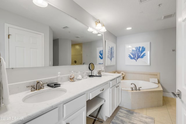 bathroom featuring tile patterned flooring, vanity, and tiled bath