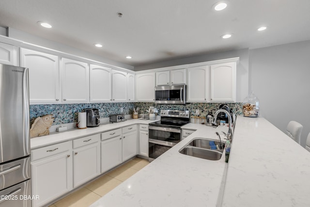 kitchen with white cabinetry, appliances with stainless steel finishes, sink, and light tile patterned floors