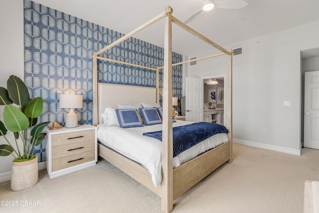 bedroom with ensuite bathroom, light colored carpet, and ceiling fan