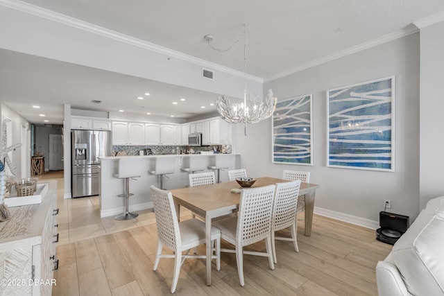 dining area with crown molding, an inviting chandelier, and light wood-type flooring