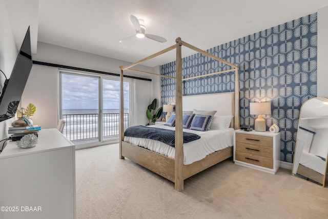 bedroom featuring a water view, light colored carpet, access to exterior, and ceiling fan