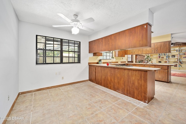 1 River Bluff Ct, Ormond Beach, FL 32174 - kitchen featuring brown cabinets, a peninsula, a ceiling fan, light tile patterned floors, and light countertops