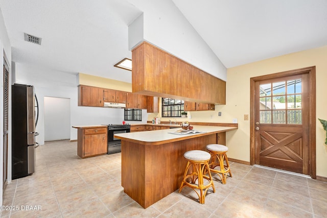 1 River Bluff Ct, Ormond Beach, FL 32174 - kitchen with freestanding refrigerator, black electric range oven, a peninsula, under cabinet range hood, and brown cabinetry