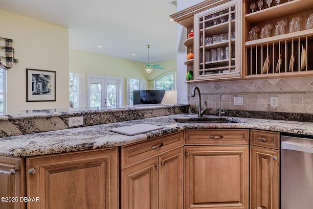 kitchen featuring sink, decorative backsplash, stainless steel dishwasher, ceiling fan, and light stone counters