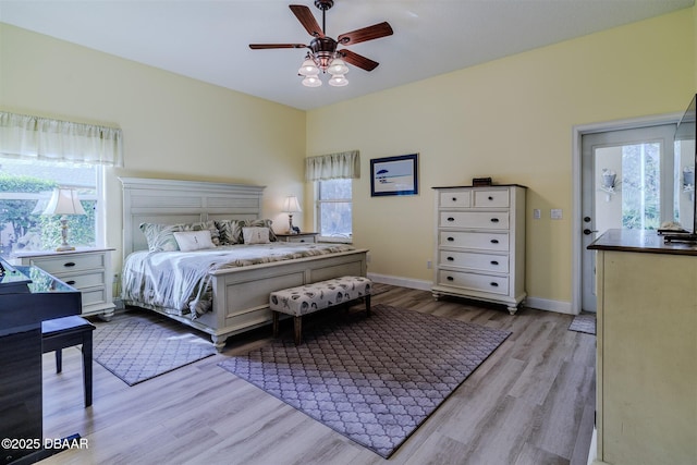 bedroom with ceiling fan, light hardwood / wood-style floors, and multiple windows