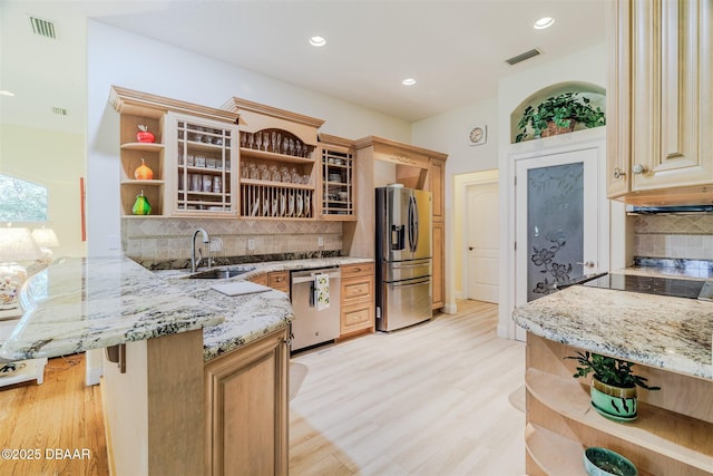 kitchen with sink, a kitchen breakfast bar, kitchen peninsula, stainless steel appliances, and light stone countertops