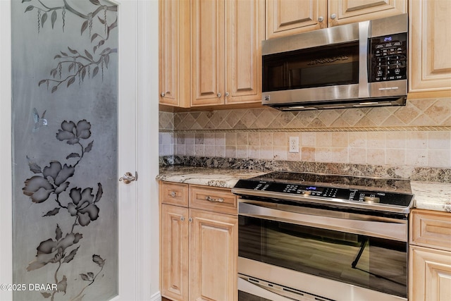 kitchen with tasteful backsplash, appliances with stainless steel finishes, light stone counters, and light brown cabinets