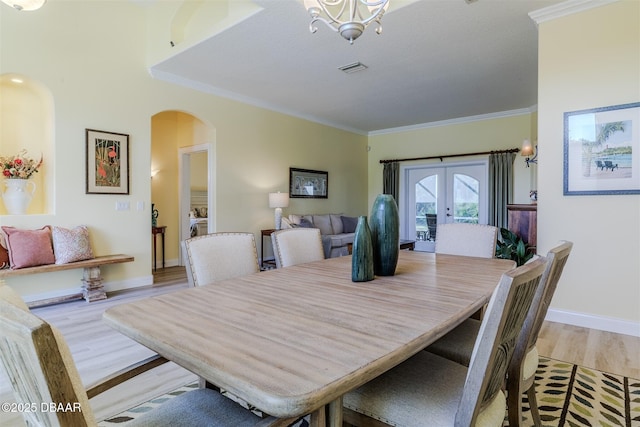 dining area with ornamental molding, light hardwood / wood-style floors, french doors, and a chandelier