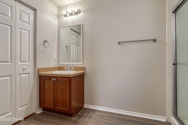 bathroom featuring an enclosed shower, vanity, and wood-type flooring