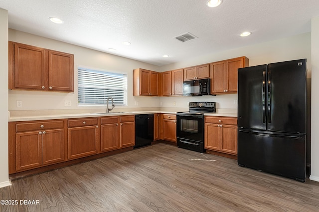 kitchen featuring dark hardwood / wood-style flooring, sink, black appliances, and a textured ceiling