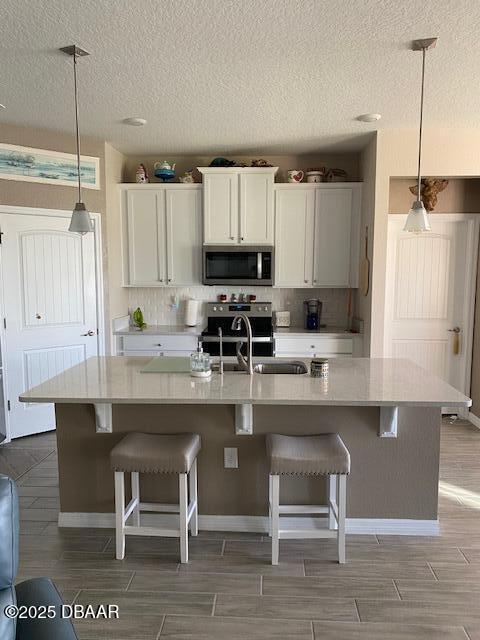 kitchen featuring hanging light fixtures, stainless steel appliances, light countertops, and wood finish floors