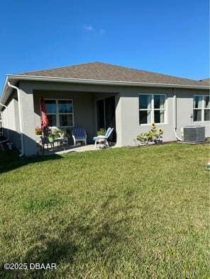 back of property with stucco siding, a lawn, and central air condition unit