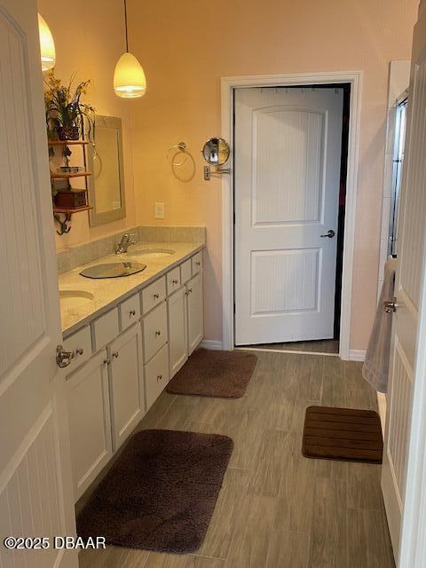 bathroom featuring double vanity, wood finished floors, a sink, and baseboards