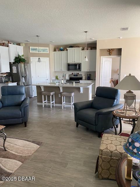 living room featuring visible vents, a textured ceiling, and wood finished floors