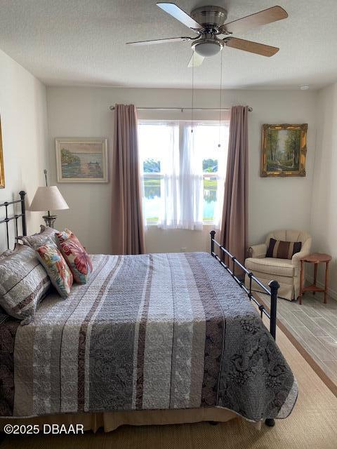 bedroom featuring ceiling fan, a textured ceiling, and wood finished floors