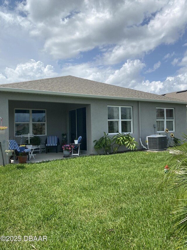 1601 Delphi Way, New Smyrna Beach, FL 32168 - back of house with stucco siding, a patio area, a lawn, and roof with shingles