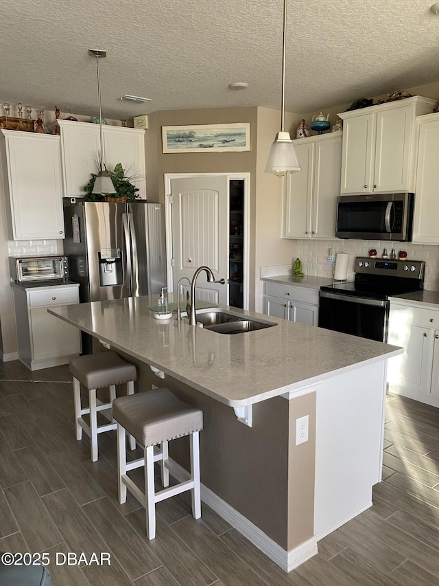 1601 Delphi Way, New Smyrna Beach, FL 32168 - kitchen with stainless steel appliances, wood finish floors, a center island with sink, a breakfast bar area, and white cabinets