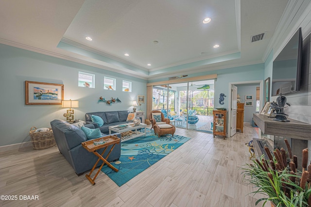 living room with a raised ceiling, light wood-type flooring, and ornamental molding