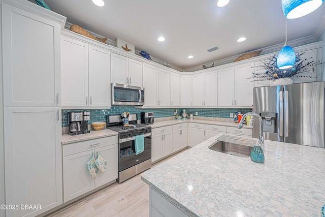 kitchen featuring sink, hanging light fixtures, white cabinets, and stainless steel appliances