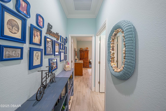 hallway with ornamental molding and light hardwood / wood-style floors