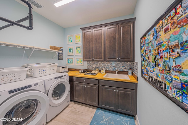 laundry room with light wood-type flooring, cabinets, washer and dryer, and sink