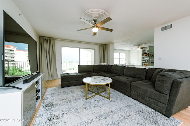 living room with ceiling fan, built in features, and light hardwood / wood-style flooring