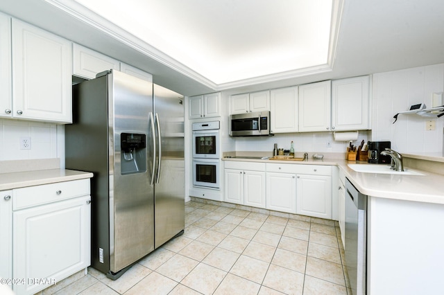 kitchen featuring appliances with stainless steel finishes, a raised ceiling, sink, white cabinets, and light tile patterned flooring