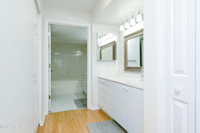 bathroom with hardwood / wood-style floors, vanity, and shower / washtub combination