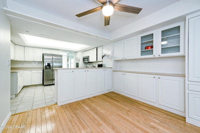 kitchen with decorative backsplash, white cabinetry, stainless steel appliances, and light hardwood / wood-style floors