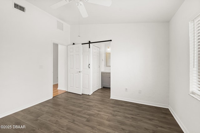 1197 Stillwood Ct, Port Orange, FL 32129 - unfurnished bedroom with baseboards, visible vents, a barn door, and dark wood-style flooring
