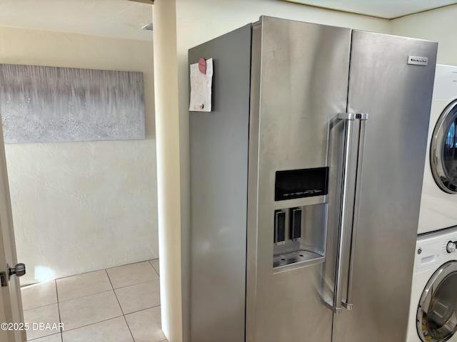 clothes washing area featuring stacked washer / dryer and light tile patterned flooring