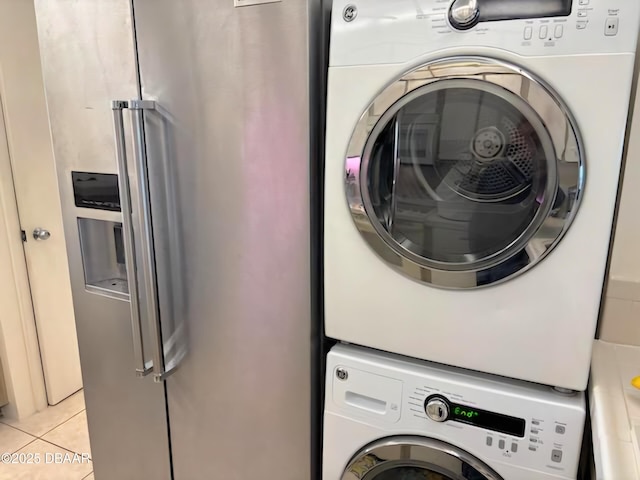 laundry area featuring stacked washer and dryer and light tile patterned flooring