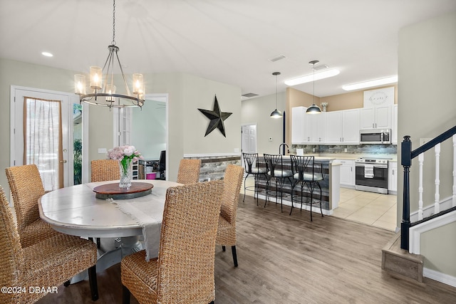 dining space with a chandelier and light hardwood / wood-style floors