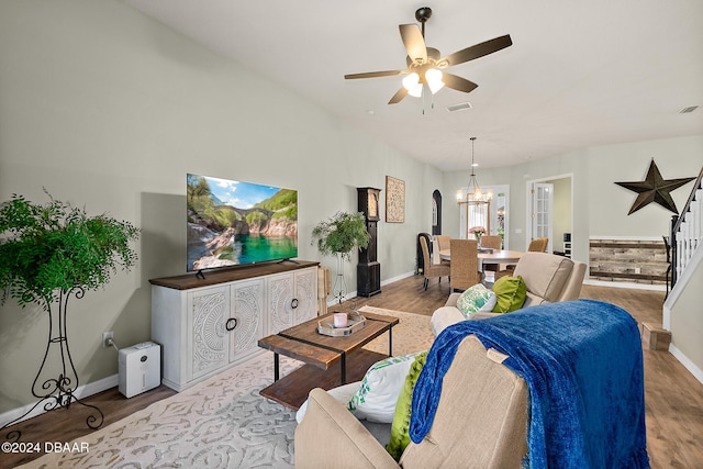 living room with ceiling fan with notable chandelier and light hardwood / wood-style flooring