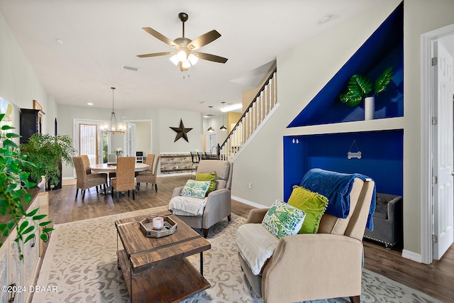 living room featuring ceiling fan with notable chandelier and wood-type flooring