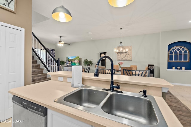 kitchen with stainless steel dishwasher, ceiling fan with notable chandelier, sink, tile patterned flooring, and hanging light fixtures