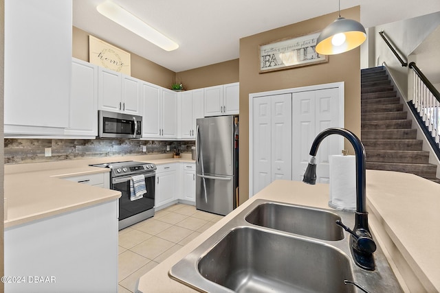 kitchen featuring appliances with stainless steel finishes, backsplash, sink, white cabinets, and hanging light fixtures