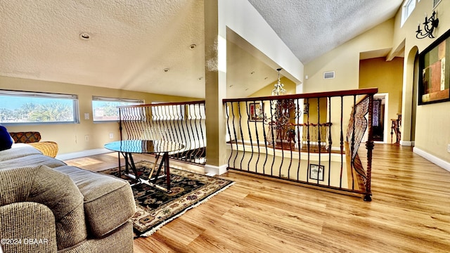 living room featuring a textured ceiling, hardwood / wood-style flooring, and high vaulted ceiling