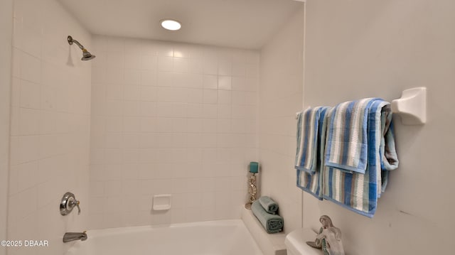 bathroom featuring tiled shower / bath and toilet