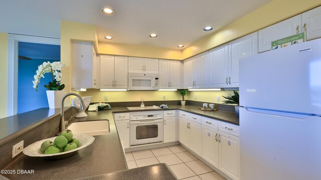 kitchen featuring light tile patterned flooring, sink, white cabinets, and white appliances