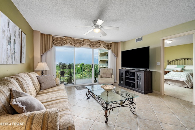 living room with a textured ceiling, light tile patterned flooring, and ceiling fan