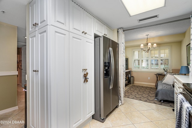 kitchen featuring hanging light fixtures, stainless steel fridge, light tile patterned floors, an inviting chandelier, and white cabinets