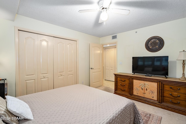 bedroom with a textured ceiling, ceiling fan, and light carpet