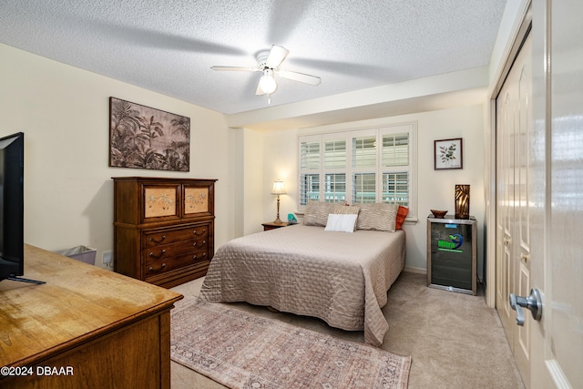 carpeted bedroom with a closet, ceiling fan, and a textured ceiling