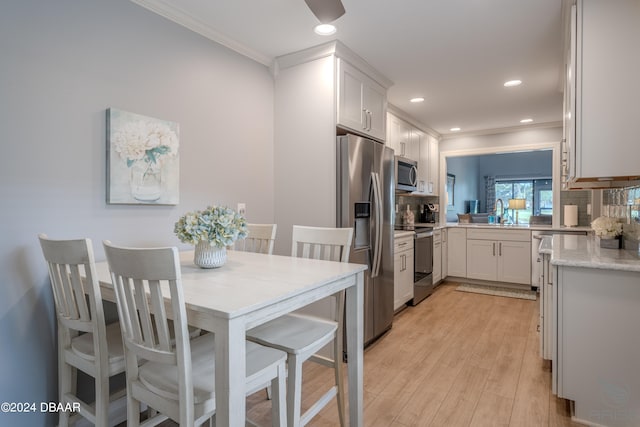 kitchen featuring white cabinets, decorative backsplash, stainless steel appliances, and light hardwood / wood-style floors