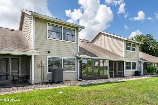 rear view of house with a lawn, central AC, and a sunroom