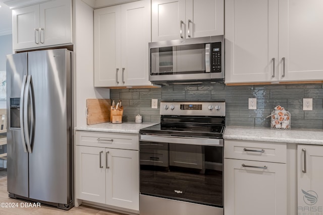 kitchen featuring white cabinetry, appliances with stainless steel finishes, light stone counters, and tasteful backsplash