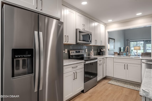 kitchen with light hardwood / wood-style flooring, appliances with stainless steel finishes, sink, and white cabinets