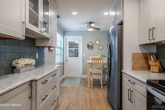 kitchen with white cabinetry, light wood-type flooring, appliances with stainless steel finishes, and ornamental molding